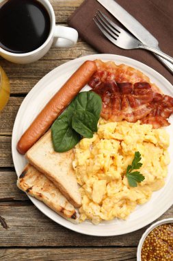 Lezzetli bir kahvaltı. Lezzetli çırpılmış yumurta, domuz pastırması ve sosis, ahşap masada servis edilir.