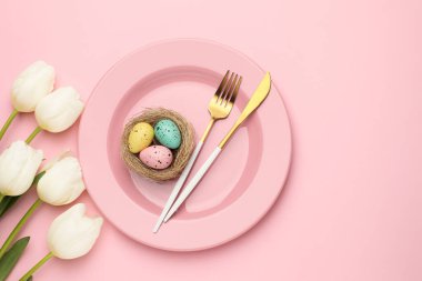 Paskalya kutlaması. Pembe arka planda boyanmış yumurtalar ve lale çiçekleri olan şenlikli masa ayarı, metin için boşluk ile düz yatıyordu.