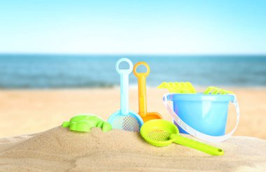 Deniz kenarındaki kumda parlak plastik plaj oyuncakları, pankart tasarımı. Yaz zamanı.