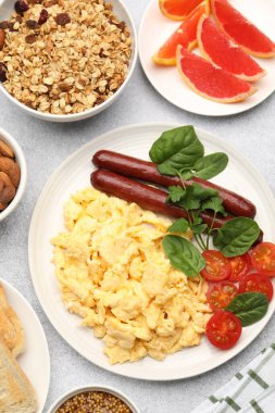 Lezzetli bir kahvaltı. Lezzetli çırpılmış yumurta, sosis ve domatesle servis edilen gri desenli masa, düz.