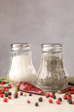 Açık gri masada baharatlı tuzluk ve biberlikler, yakın plan.