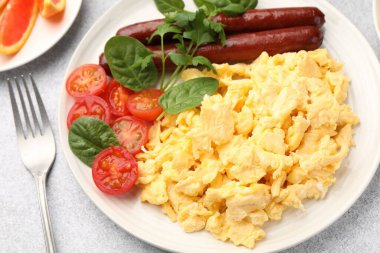 Lezzetli bir kahvaltı. Lezzetli çırpılmış yumurta, sosis ve domatesler gri desenli masa, yakın plan.