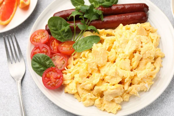 Lezzetli bir kahvaltı. Lezzetli çırpılmış yumurta, sosis ve domatesler gri desenli masa, yakın plan.