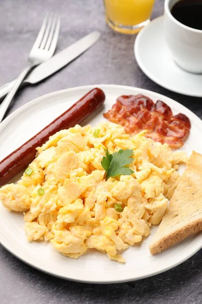 Lezzetli bir kahvaltı. Lezzetli omlet, domuz pastırması, sosis ve ekmek gri masada servis edilir, yakın plan.