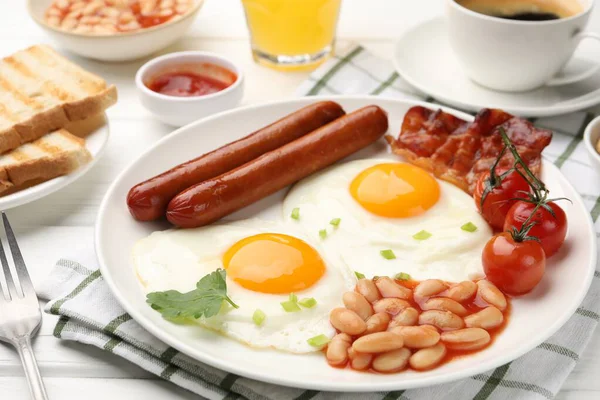 Geleneksel İngiliz kahvaltısı. Lezzetli, güneşli, pastırmalı yumurta ve sosisler beyaz ahşap masada servis ediliyor, yakın plan.