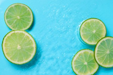 Açık mavi arka planda limon dilimleri, düz bir zemin. Metin için boşluk