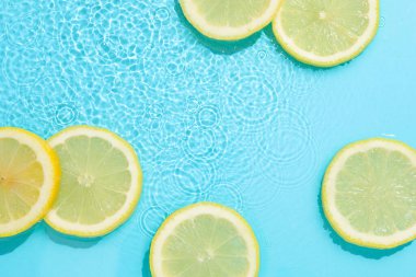 Açık mavi arka planda limon dilimleri, düz. Metin için boşluk