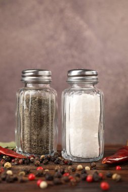 Ahşap masada baharatlı tuzluklar ve biberlikler bulanık arka planda, yakın plan