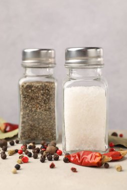 Açık gri masada baharatlı tuzluk ve biberlikler, yakın plan.