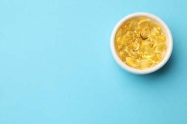 Açık mavi arka planda altın jelatin kapsüller, üst manzara. Metin için boşluk