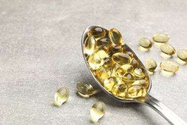 Açık gri masada altın jelatin kapsüllü kaşık, yakın plan. Metin için boşluk