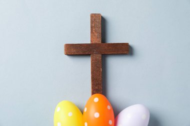 Ahşap haç ve açık gri arka planda Paskalya yumurtaları düz yatıyordu.