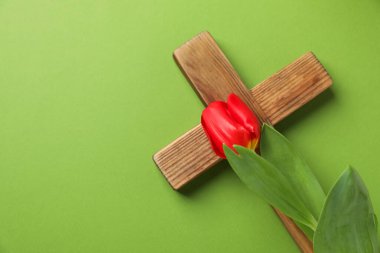 Paskalya özellikleri. Ahşap haç ve yeşil arka planda güzel lale, üst manzara. Metin için boşluk