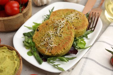 Mikroyeşillikli lezzetli vejetaryen köfteler ve gri masada salata, yakın plan.