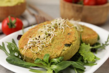 Mikroyeşillikli lezzetli vejetaryen köfteler ve gri masada salata, yakın plan.