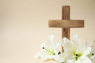 Paskalya. Ahşap haç ve bej arka planda güzel zambak çiçekleri, metin için boşluk ile yakın plan