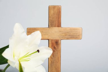 Paskalya. Ahşap haç ve gri arka planda güzel zambak çiçeği, yakın plan.