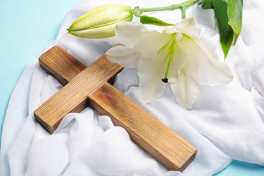 Paskalya. Tahta haç, beyaz bez ve açık mavi arka planda güzel zambak çiçekleri, yakın plan.