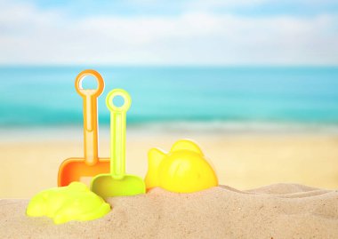 Deniz kenarındaki kumda parlak plastik plaj oyuncakları. Yaz zamanı.