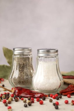 Açık gri masada baharatlı tuzluk ve biberlikler, yakın plan.