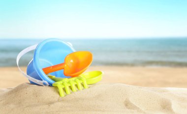 Deniz kenarındaki kumda parlak plastik plaj oyuncakları, pankart tasarımı. Yaz zamanı.