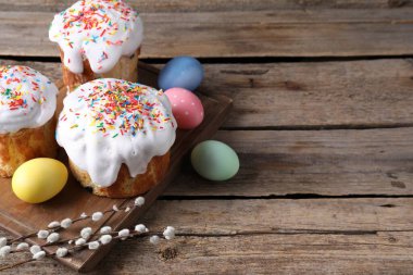 Lezzetli Paskalya pastaları, boyanmış yumurtalar ve söğüt dalları ahşap masada, yazı için yer.