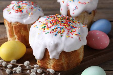 Lezzetli Paskalya pastaları, boyanmış yumurtalar ve söğüt dalları ahşap masada, yakın plan.