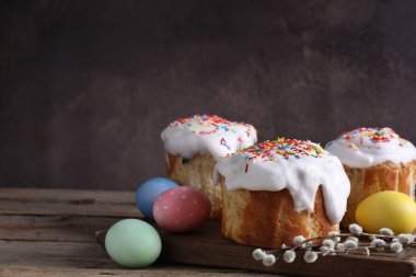 Lezzetli Paskalya pastaları, boyanmış yumurtalar ve tahta masanın üzerinde söğüt dalları, yakın plan. Metin için boşluk