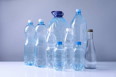 Beyaz masada gri arka planda farklı boyutlarda su şişeleri