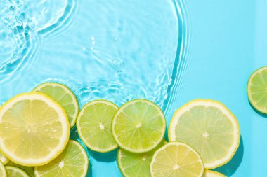Açık mavi arka planda limon ve limon dilimleri, düz. Metin için boşluk