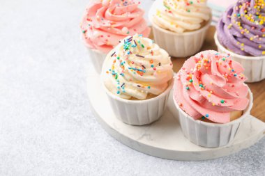 Açık gri masaya serpiştirilmiş enfes kekler, yakın plan. Metin için boşluk