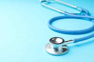 Açık mavi arka planda steteskop, yakın plan. Metin için boşluk