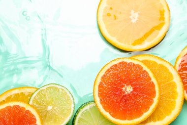 Turkuaz arka planda sudaki narenciye dilimleri, düzlük.