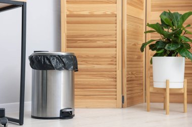 Kapalı mekanda yerde plastik torba olan metal çöp kutusu, metin için yer