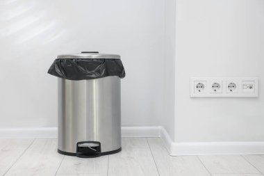 Kapalı mekanda yerde plastik torba olan metal çöp kutusu, metin için yer