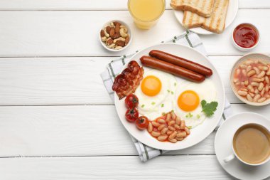 Geleneksel İngiliz kahvaltısı. Lezzetli, güneşli, domuz pastırmalı yumurtalar ve beyaz ahşap masada servis edilen sosisler, düz yatak. Metin için boşluk