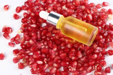 Beyaz arka planda gerekli yağ ve nar tohumları, yakın plan.