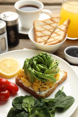 Avokado tostlu lezzetli kahvaltı ahşap masada servis edilir, yakın plan.