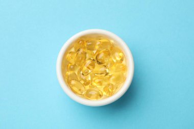 Açık mavi arka planda altın jelatin kapsüller, üst manzara.