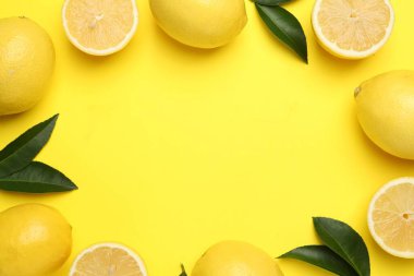 Sarı arka planda olgun limon ve yaprakların çerçevesi düz. Metin için boşluk