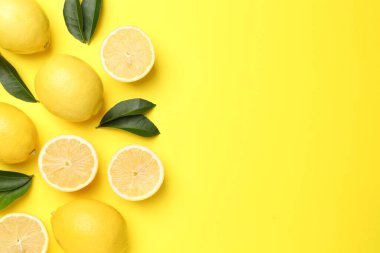 Olgun limon ve yapraklar sarı arka planda, düz yerde. Metin için boşluk