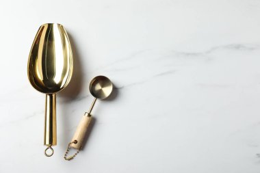 Altın kepçeler beyaz mermer masada, düz yerde. Metin için boşluk