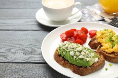 Gri ahşap masada servis edilen lezzetli avokado tostlu sağlıklı bir kahvaltı. Metin için boşluk