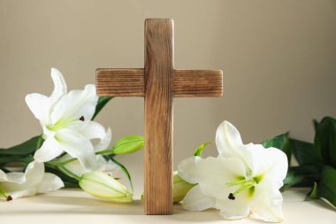 Paskalya. Ahşap haç ve bej arka planda güzel zambak çiçekleri, yakın plan.