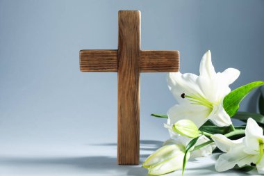 Paskalya. Ahşap haç ve gri arka planda güzel zambak çiçekleri, yakın plan.