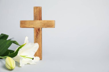Paskalya. Ahşap haç ve gri arkaplanda güzel zambak çiçekleri, metin için boşluk ile yakın plan