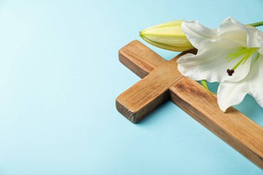 Paskalya. Ahşap haç ve açık mavi arkaplanda güzel zambak çiçekleri, metin için yere yakın çekim