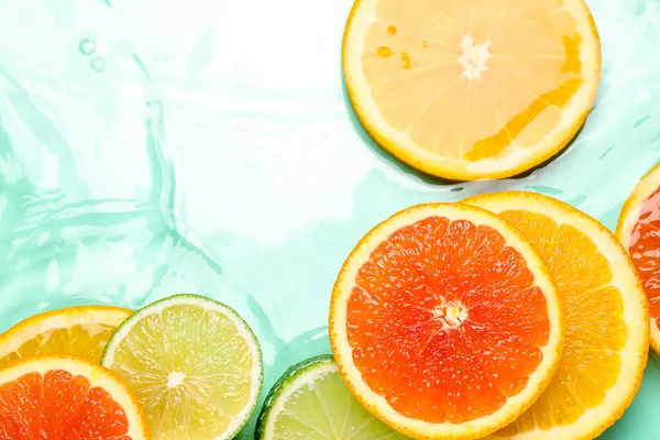 Turkuaz arka planda sudaki narenciye dilimleri, düzlük.