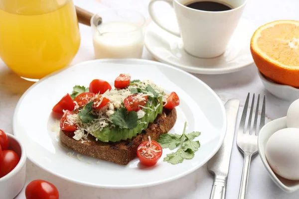 Beyaz masada servis edilen lezzetli avokado tostlu sağlıklı bir kahvaltı.
