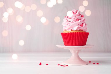 Sevgililer Günün kutlu olsun. Kremalı tatlı kek ve kırmızı kalp şeklinde serpiştirilmiş masa, bokeh ışıkları